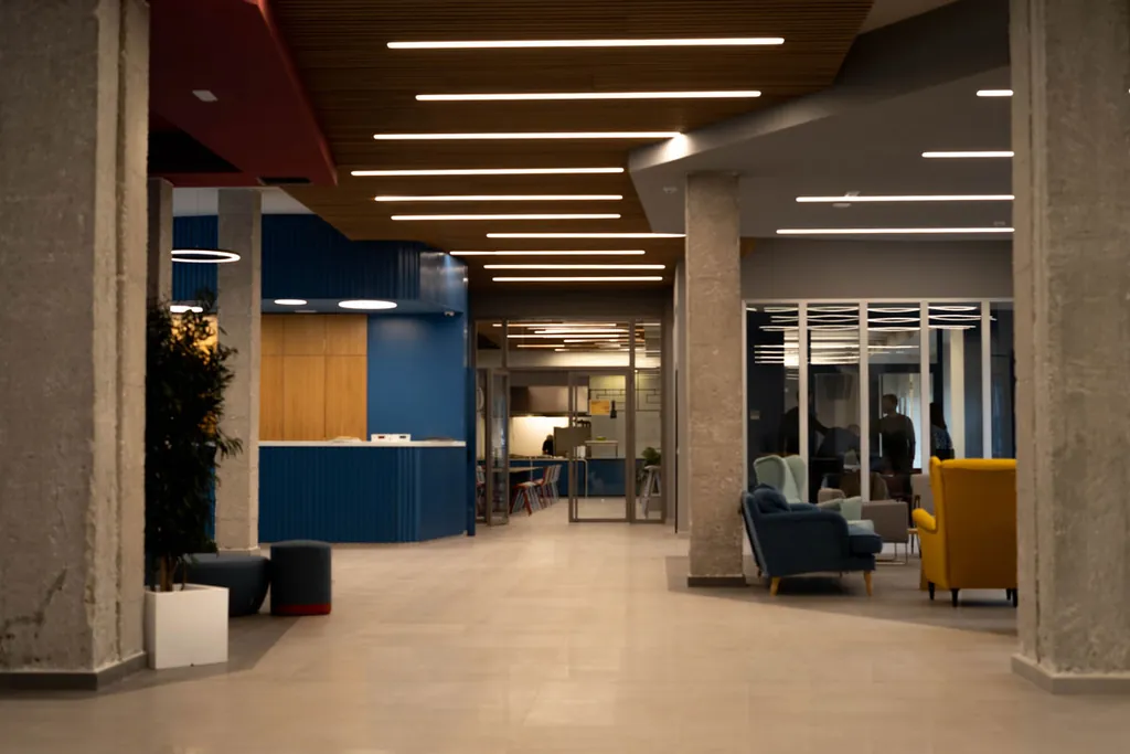 Zona de estar del hall con butacas azules y amarillas junto a la cafetería